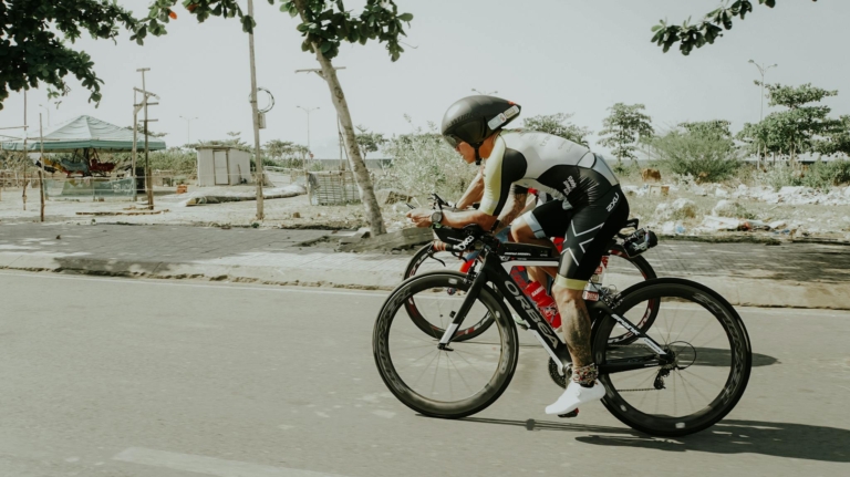 Cyclists in sportswear biking on a road in Nha Trang, Vietnam.