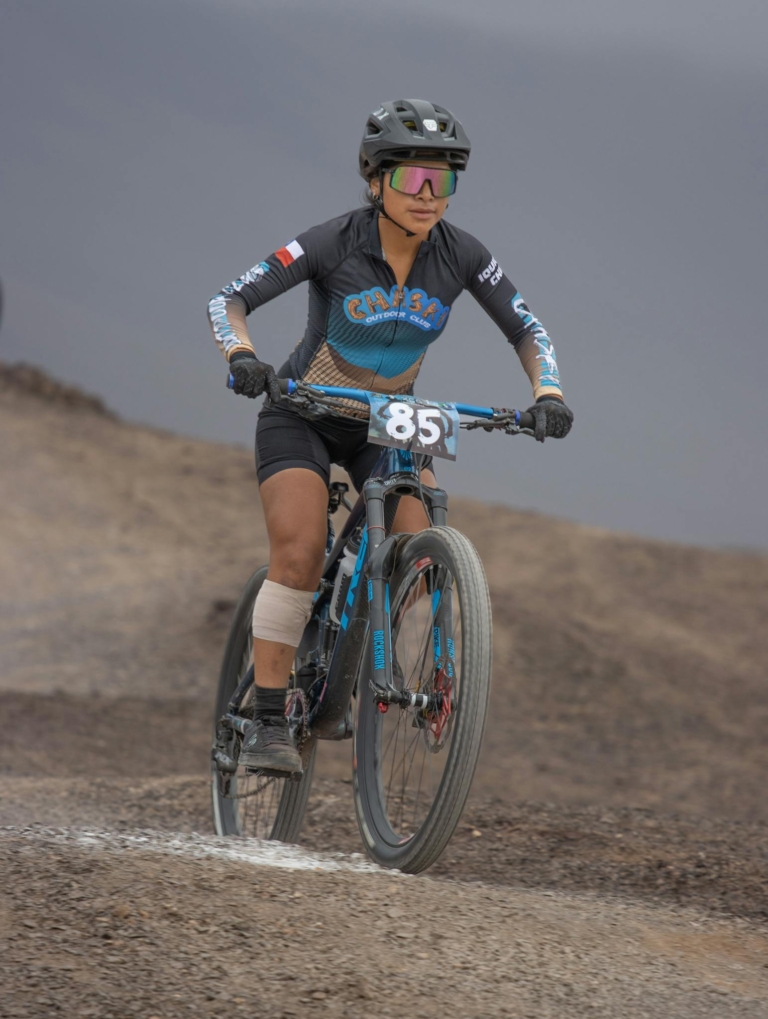 Dynamic portrait of a woman mountain biking on challenging outdoor terrain, showcasing athleticism and determination.